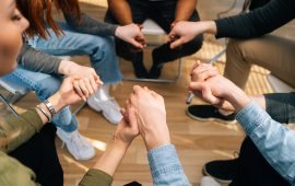 Close-up top view of group diverse multiethnic people holding hands together during the psychological therapy, meditating and solving together mental problems. Concept of consulting of mental problem